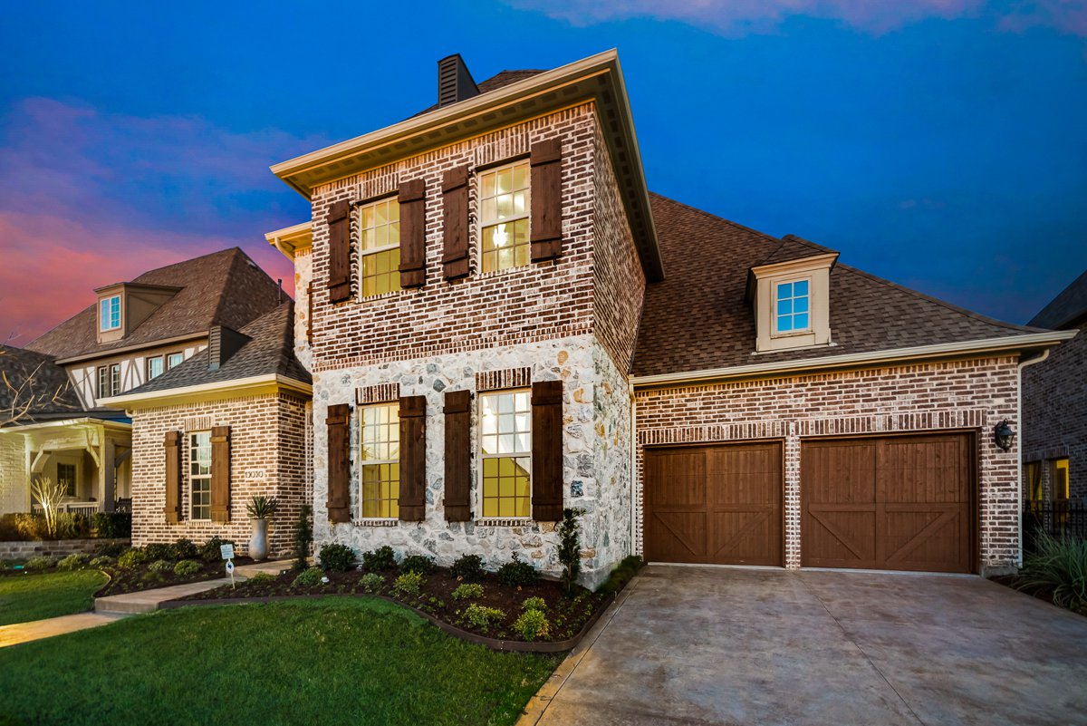 Two-story brick and stone home at twilight, marketed by the Todd Tramonte Home Selling Team