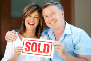 happy couple holding a real estate SOLD sign