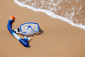 snorkeling gear on beach sand with ocean water