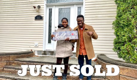 Happy home buyers holding a Sold by Jerry Mac sign in front of their new home