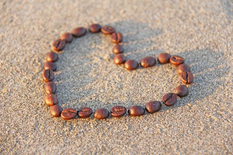 Coffee beans making a heart in the sand