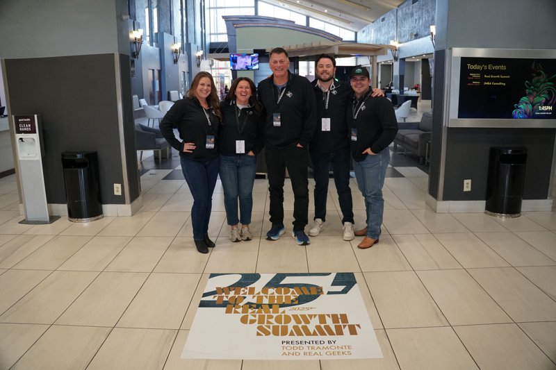 Five team members standing together in a conference venue lobby