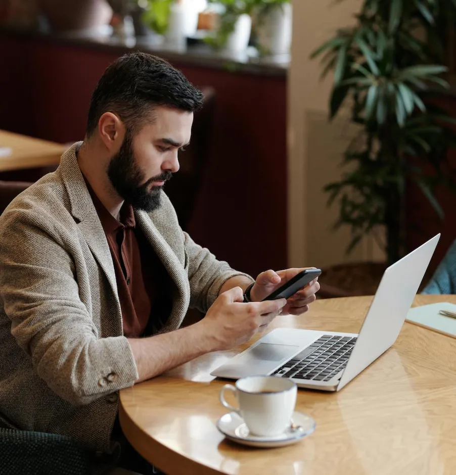 person using a phone and a laptop