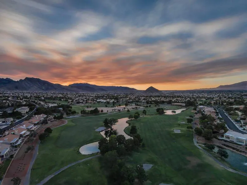 Golf course and surrounding homes beneath a colorful sunset sky